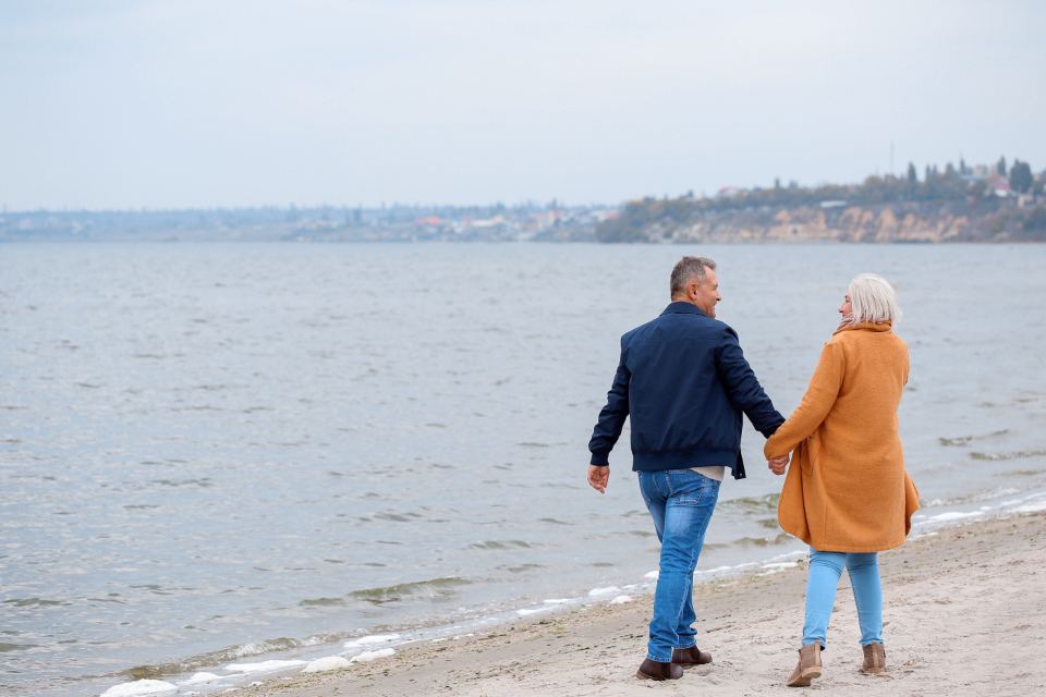 Pareja mayor caminando de la mano junto al mar